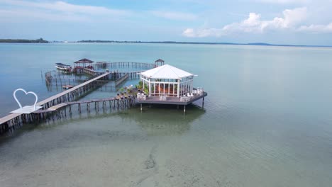 Beautiful-aerial-drone-view-of-a-restaurant-in-the-middle-of-the-sea-with-a-wooden-bridge-in-Leebong-Island,-Belitung-Indonesia