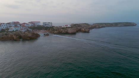 Motorboat-reaching-Baleal-Village-with-sandy-beach-and-white-buildings-in-Portugal