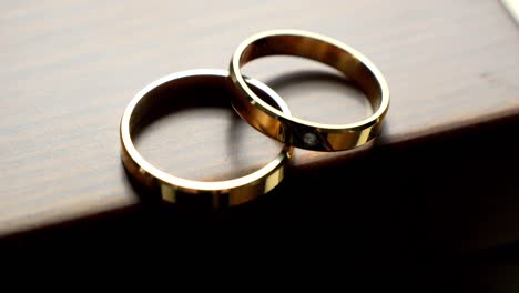 Two-golden-wedding-rings,-one-adorned-with-a-precious-gemstone