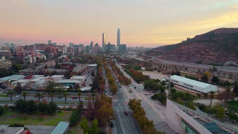 Drone-Dolly-En-Una-Toma-Espectacular-Del-Horizonte-De-Santiago-De-Chile-Con-Una-Puesta-De-Sol-Naranja-En-El-Parque-Bicentenario-De-Vitacura