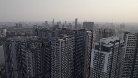 Residential-area-in-Ho-Chi-Minh,-Saigon,-Vietnam,-ascending-and-unveiling-the-city-center-in-the-background,-aerial-drone-video-during-sunset-reveal-shot