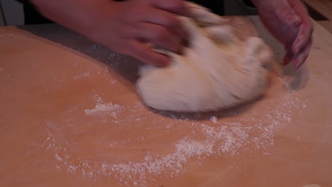 Woman-kneading-dough-in-flour-on-wooden-table