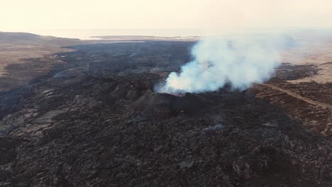 Erupting-volcano-with-smoking-crater-in-black-rock-volcanic-wasteland