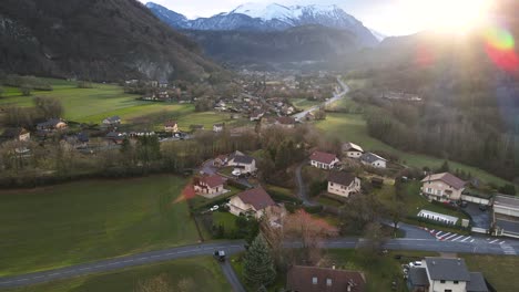 Sunrise-over-a-small-town-surrounded-by-green-grass-and-mountains