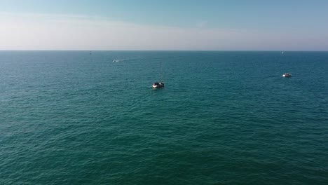 Two-boats-sailing-on-the-tranquil-blue-waters-of-garraf-costa,-barcelona,-under-clear-skies,-aerial-view