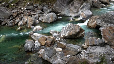 Stunning-green-clear-waters-of-Verzasca-Switzerland-flow-across-boulders-polishing-stones