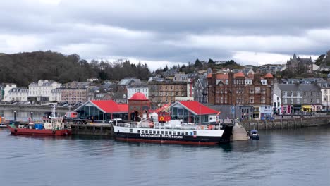 Scenic-landscape-view-of-Oban-town,-waterfront,-and-buildings-with-Caledonian-Macbrayne-ferry-in-forefront,-Western-Scotland-UK