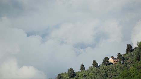 Einsames-Haus-Auf-Einem-Hügel-Mit-Schnell-Ziehenden-Wolken-Bei-Sonnigem-Wetter,-Zeitraffer