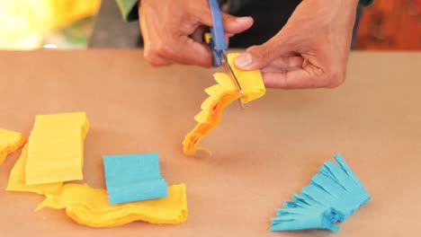 Papercraft-lesson-cutting-colorful-crepe-paper-with-scissors,-closeup-on-hands