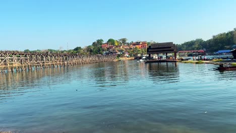 A-DJI-Mini-4-drone-gracefully-advances-over-the-Kwai-Yai-River,-capturing-stunning-aerial-views-of-Kanchanaburi,-Thailand