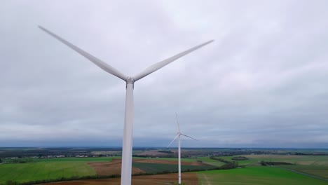 wind-turbine-in-close-up,-low-angle-and-drone-tracking-at-sunset,-French-landscape
