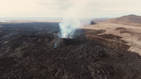 Vulkanlandschaft-Aus-Schwarzem-Fels-Mit-Ausbrechendem-Aktiven-Vulkan-In-Island