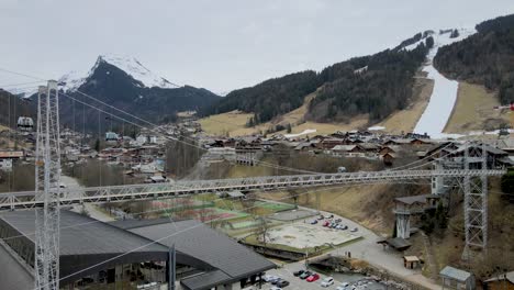 Schneefreier-Französischer-Skiort-Morzine-Mit-Fußgängerbrücke-Und-Seilbahnen-Und-Pleney-Skipiste-Im-Hintergrund