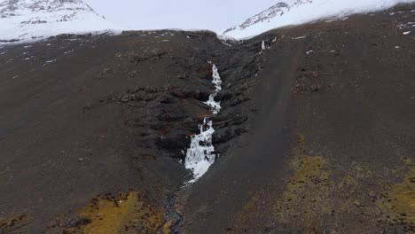 Gefrorener-Skutafoss-Wasserfall,-Der-Von-Schneebedeckten-Gletscherbergen-Herabstürzt