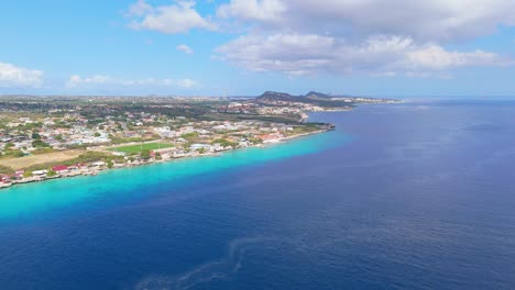 Panoramic-aerial-dolly-showcases-gentle-sloping-sandy-drop-off-to-clear-blue-waters-of-Curacao-coastline