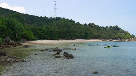 Locked-off-view-over-sandy-bay-at-low-tide-with-parked-jet-skis