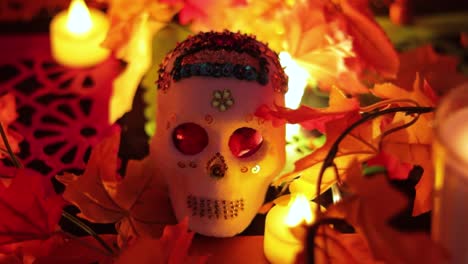 Sugar-skull-with-sequins-and-orange-lights-and-leaves,-close-up