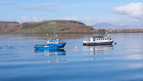 Small-fishing-and-tour-boats-moored-in-Oban-bay-in-gentle-swell-on-a-sunny-blue-sky-day-in-popular-tourism-destination,-Western-Scotland-UK