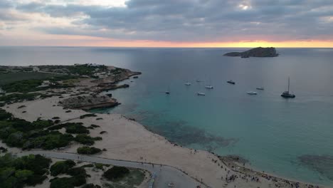 Playa-De-Cala-Comte-Con-Barcos,-Impresionante-Cielo-Al-Atardecer-En-Ibiza