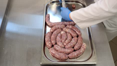 The-butcher-fills-pork-casings-with-a-meat-mixture,-creating-sausage-intended-for-thermal-processing-in-the-oven