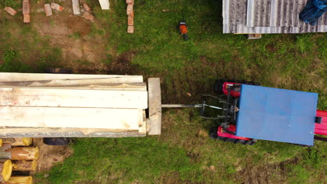 Aerial-top-down-shot-of-tractor-transporting-logs-of-wood-on-trailer-at-sawmill-factory