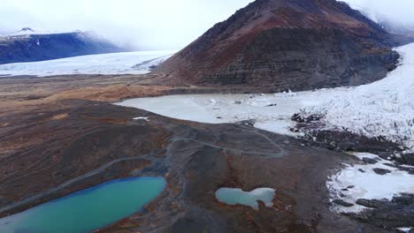 Glacial-lakes-below-melting-glacier-ice-sheet-in-foggy-mountain-valley