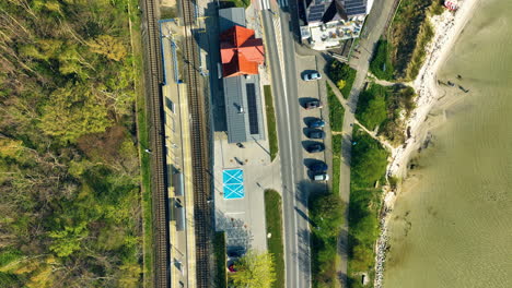 Bird's-eye-view-of-a-railway-station-in-Kuźnica,-showing-the-juxtaposition-of-train-tracks,-roadways,-and-the-adjacent-sea,-encapsulating-the-unique-infrastructure-of-this-coastal-area---Aerial