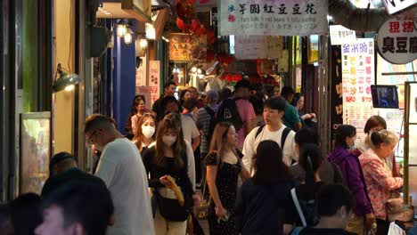 Los-Viajeros-Deambulan-Por-Una-Animada-Calle-Estrecha-Flanqueada-Por-Puestos-De-Comida,-Boutiques-De-Souvenirs-Y-Pintorescas-Tiendas-De-Regalos-En-La-Antigua-Calle-Jiufen,-Un-Encantador-Pueblo-De-Montaña-En-Taiwán.