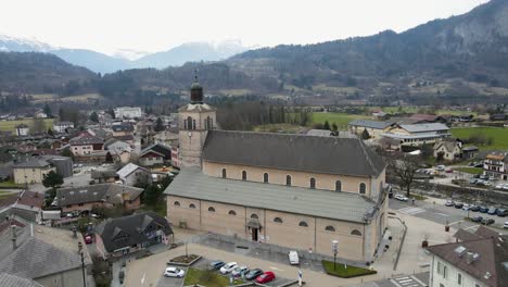 Aerial-shot-of-a-tan-church-located-in-a-small-French-town