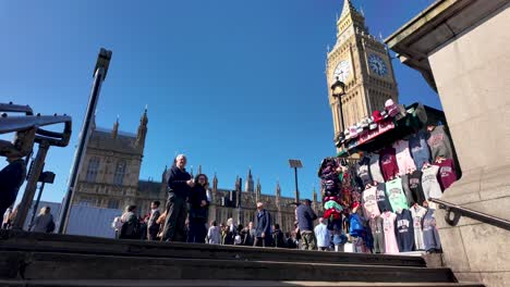 Pedestrians-leisurely-walk-by-Big-Ben,-with-the-Houses-of-Parliament-alongside-the-Westminster-Station-exit,-capturing-the-essence-of-iconic-landmarks-and-urban-exploration