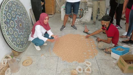 In-Einer-Traditionellen-Fez-Töpferei-Wählt-Ein-Arbeiter-Geschickt-Mosaikstücke-Aus-Und-Fügt-Sie-Zusammen,-Um-Ein-Großes-Kreisförmiges-Objekt-Zu-Erstellen.