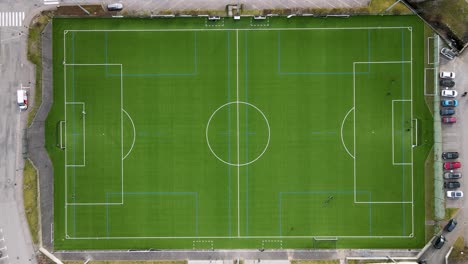 Vista-Superior-De-Un-Campo-De-Fútbol-Cuadrado-Verde-Y-Algunos-Niños-Jugando-A-La-Pelota-En-él