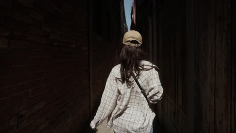 Rear-Of-A-Woman-Walking-On-The-Alley-Through-Brick-Wall-Buildings-In-Venice,-Italy