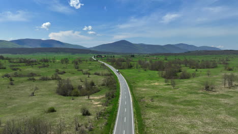 Aerial-shot-of-a-road-that-stretches-across-a-mountain-plateau-overgrown-with-grass-and-groves