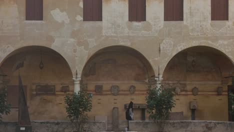 Woman-Is-Walking-In-Historic-Architecture-With-Arch-Covered-Passage-In-Venice,-Italy