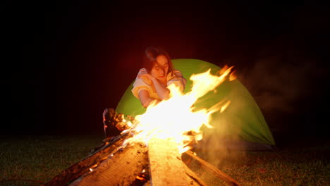 portrait-of-lonely-asiatic-woman-in-front-of-bonfire-while-camping-outdoor