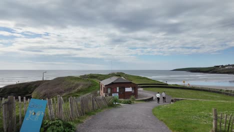 Inchidoney-beach-and-cliff,-an-area-arranged-for-sitting-with-information-panel-and-few-people-walking,-exploring