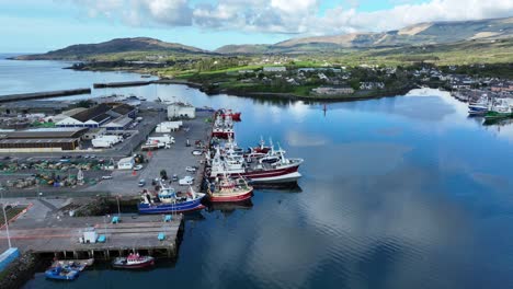 Drone-flying-over-Castletownbere-harbour-with-fishing-boats-being-prepared-to-unload-and-go-to-sea-again-early-summer-morning-in-west-Cork-Ireland