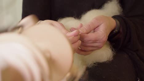 Artisan-hands-pull-wool-being-twisted-by-modern-spinning-wheel-bobbin