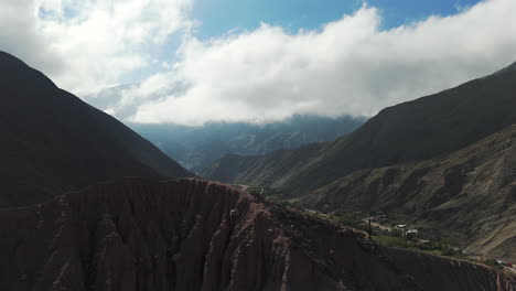 Aerial-view-of-the-Purmamarca-valley,-Drone-flying-between-high-mountains-in-Jujuy-province,-Argentina
