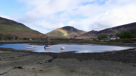 Scenic-landscape-view-of-natural-beauty-in-outdoor-nature-with-shallow-ocean-water,-sail-boats,-and-rugged-mountains-on-the-Isle-of-Arran,-Western-Scotland-UK