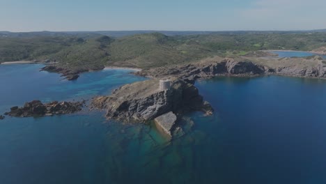 Drone-Volar-Acantilado-De-Montaña-Gris-Contrastando-El-Paisaje-Boscoso-Del-Mar-Azul-En-Menorca