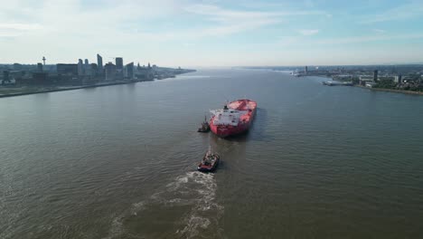 Colourful-massive-oil-tanker-sailing-up-River-Mersey---aerial-drone-anti-clockwise-rotate,-revealing-Liverpool-cityscape,-England,-UK