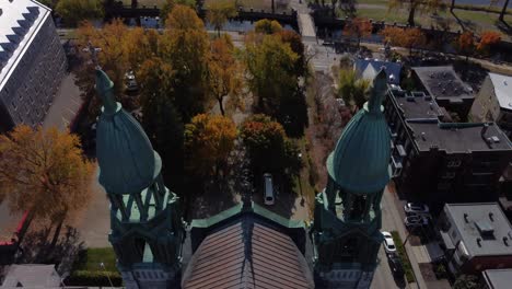 Aerial-close-up-of-Paroisse-Saints-Anges-Church-dome,-drone-revealing-cityscape-of-Montreal-at-distance-during-a-sunny-day-of-summer