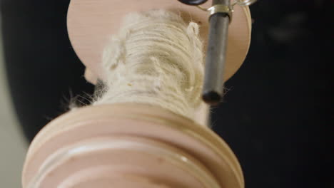 Closeup-spinning-wheel-detail:-Yarn-spins-onto-fibre-craft-bobbin