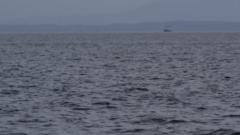 Küstenwasseroberfläche-Mit-Boot-Unscharf-Vor-Dunstiger-Bergkulisse