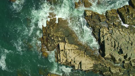 Static-drone-view-of-a-rocky-coast-in-Portland,-Maine-on-a-sunny-afternoon