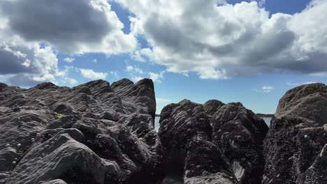 Dramatic-sky-with-puff-white-clouds-on-blue,-with-layers-of-rock-formation-with-muscles-glued-on-it
