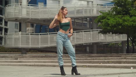 En-Medio-De-La-Riqueza-Cultural-De-Un-Centro-Urbano-Caribeño,-Una-Chica-Con-Jeans-Y-Botas-Deambula,-Con-Edificios-Altos-Creando-Un-Pintoresco-Telón-De-Fondo.