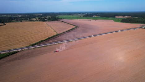 Aerial-pan-follows-tractor-and-dust-smoke-cloud-rising-behind-in-rural-countryside